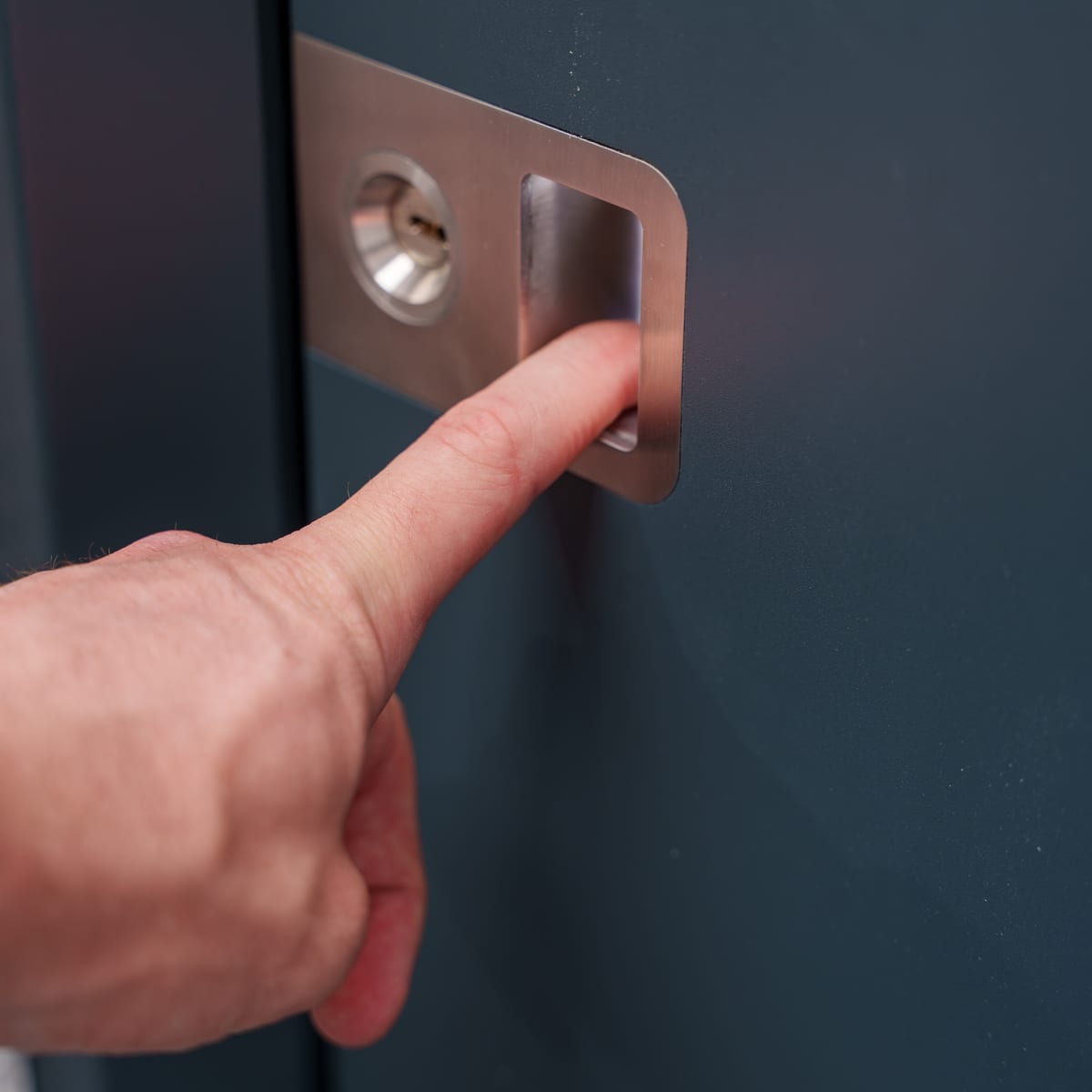 Fingerabdrucksensor in der Edelstahl-Griffmulde einer anthrazitfarbenen Haustür, direkt neben dem Profilzylinder