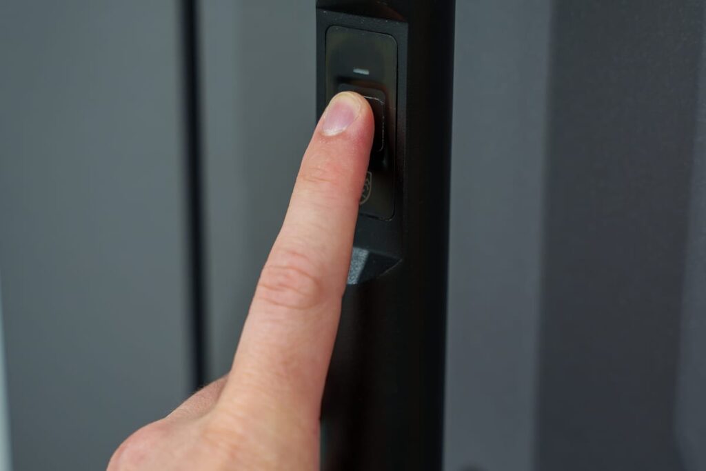 Fingerprint an der Haustür nachgerüstet: Zeigefinger liegt auf dem Fingerabdrucksensor im schwarzen Türprofil